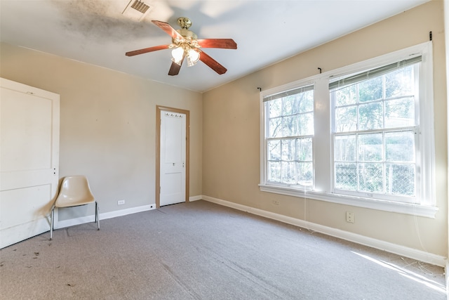 carpeted spare room with ceiling fan and plenty of natural light