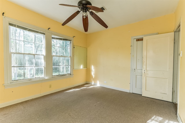 carpeted empty room with ceiling fan and plenty of natural light