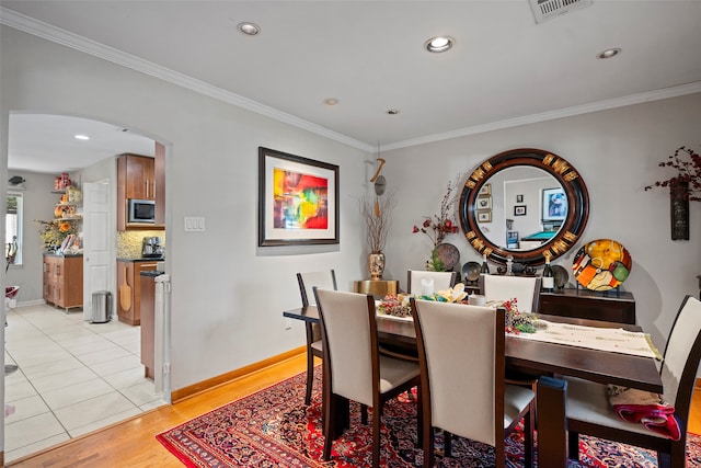 dining space featuring ornamental molding and light tile patterned floors