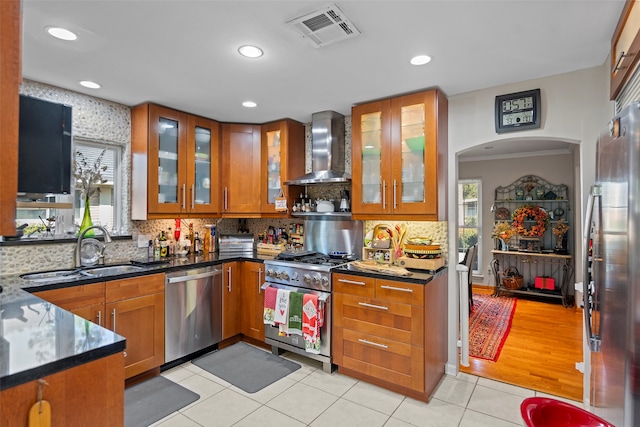 kitchen featuring wall chimney exhaust hood, appliances with stainless steel finishes, sink, and a healthy amount of sunlight