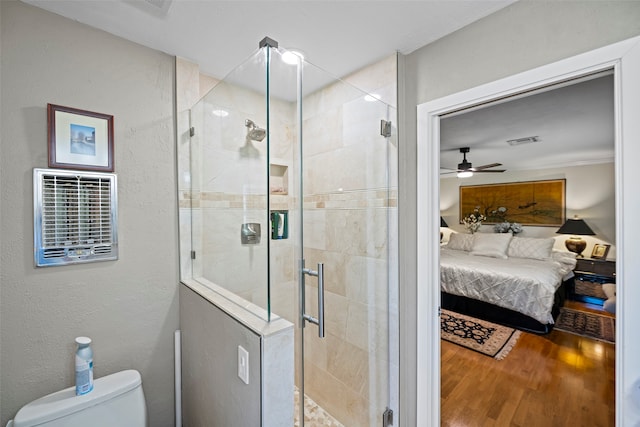 bathroom featuring ceiling fan, hardwood / wood-style flooring, toilet, and an enclosed shower