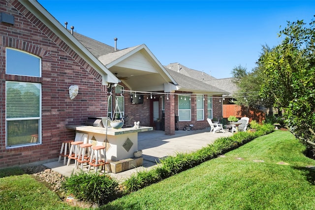 rear view of house with a patio area, exterior bar, and a lawn