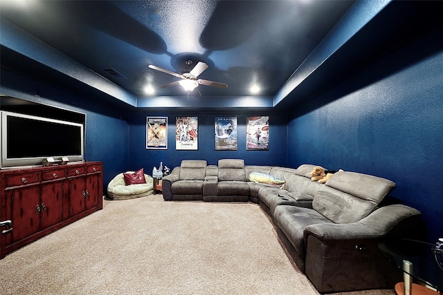 carpeted home theater with a tray ceiling and ceiling fan