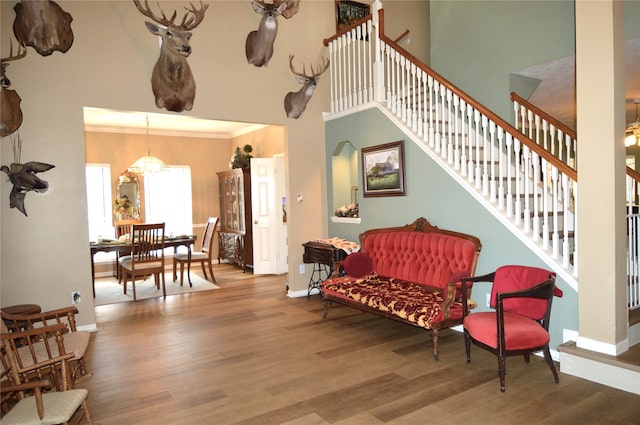 sitting room featuring hardwood / wood-style floors, a towering ceiling, a chandelier, and ornamental molding