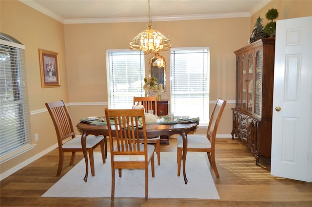 dining room with wood-type flooring, an inviting chandelier, and ornamental molding