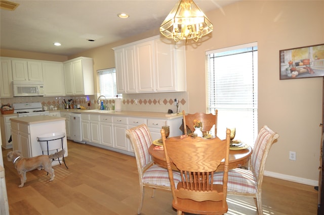 kitchen with backsplash, white appliances, sink, white cabinets, and light hardwood / wood-style floors