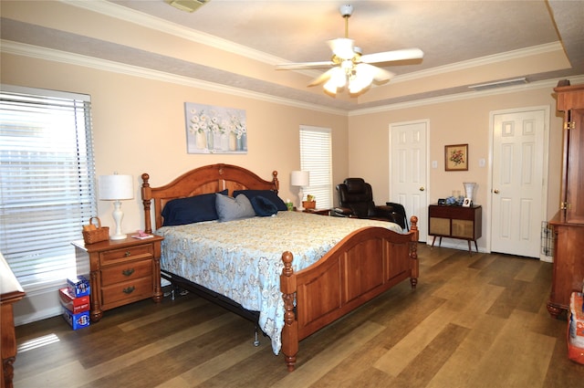 bedroom with dark hardwood / wood-style flooring, a tray ceiling, ceiling fan, and ornamental molding