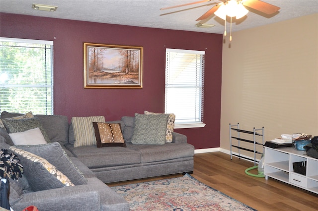 living room featuring wood-type flooring, a textured ceiling, and ceiling fan