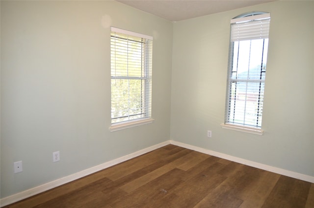 unfurnished room featuring dark hardwood / wood-style flooring and a wealth of natural light