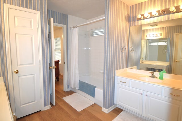 bathroom with hardwood / wood-style floors, vanity, and shower / tub combo