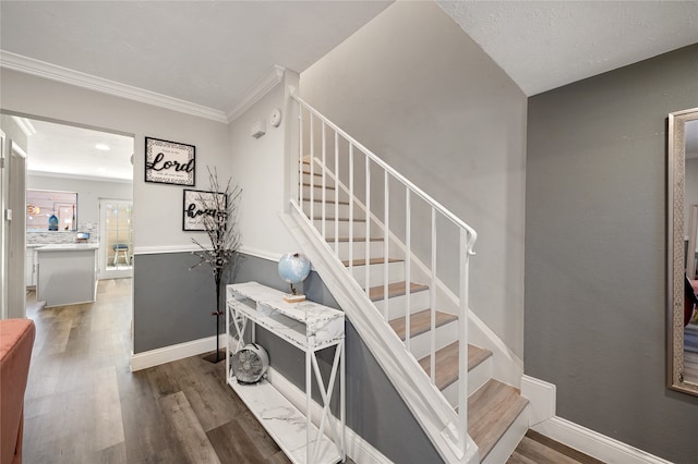 stairway with ornamental molding and hardwood / wood-style flooring