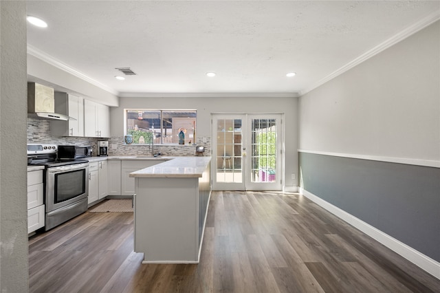 kitchen featuring wall chimney range hood, electric range, white cabinetry, dark wood-type flooring, and crown molding