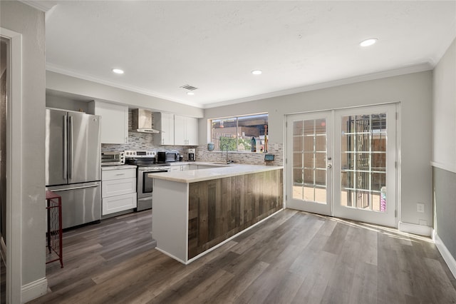 kitchen with wall chimney range hood, dark hardwood / wood-style floors, kitchen peninsula, stainless steel appliances, and white cabinetry