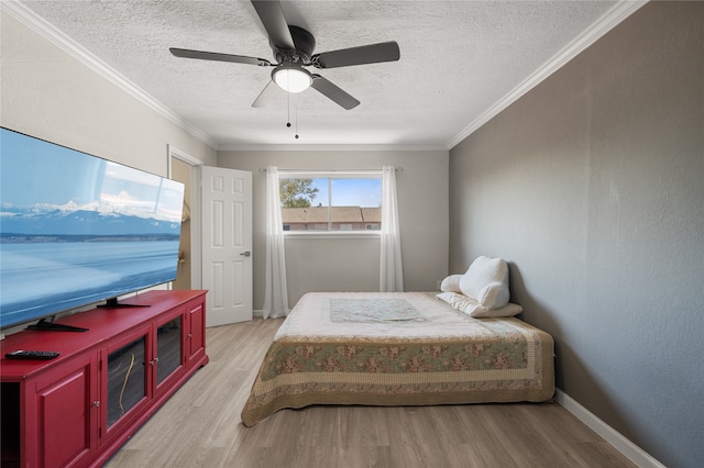 bedroom featuring crown molding, light hardwood / wood-style flooring, a textured ceiling, and ceiling fan