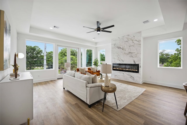 living room with ceiling fan, hardwood / wood-style flooring, a fireplace, and a tray ceiling