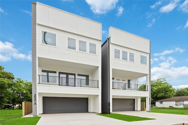 contemporary home featuring a garage, a front yard, and a balcony