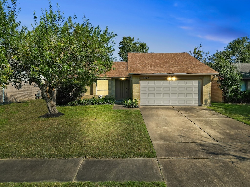 ranch-style house featuring a garage and a front lawn