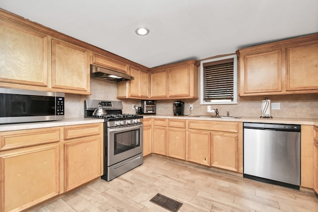 kitchen with light brown cabinets, exhaust hood, light hardwood / wood-style flooring, stainless steel appliances, and sink