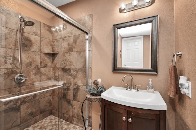 bathroom featuring a shower with door and vanity