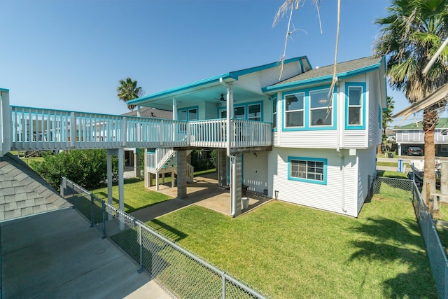 rear view of house with a wooden deck, a lawn, and a patio area