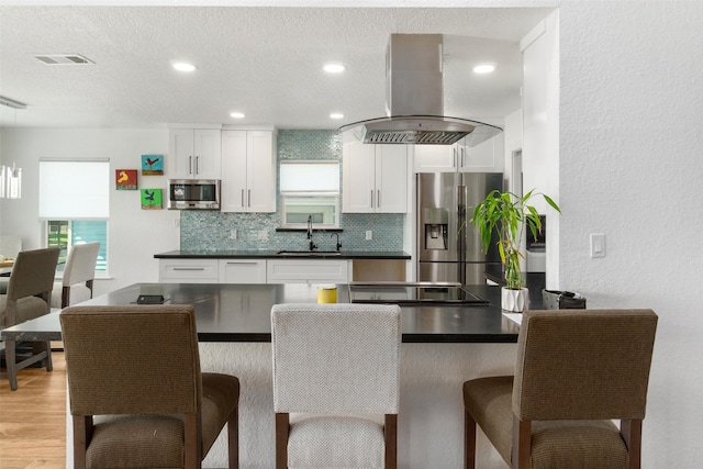 kitchen featuring stainless steel appliances, white cabinets, sink, light hardwood / wood-style floors, and island range hood