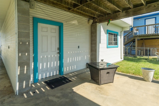 property entrance with a patio, a lawn, and a wooden deck