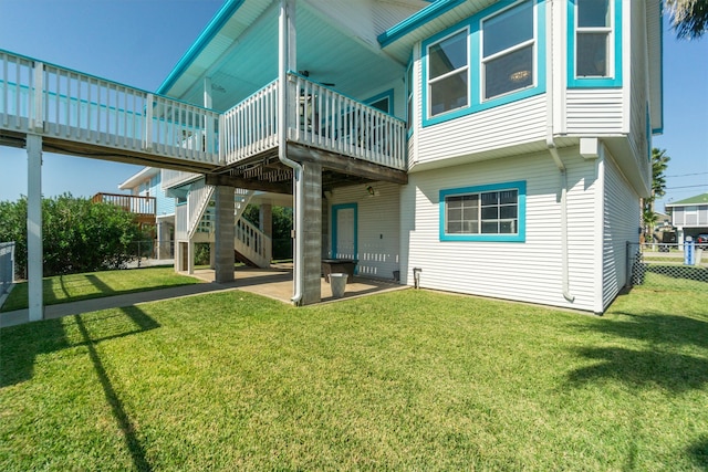 rear view of house with a yard, a wooden deck, and a patio area