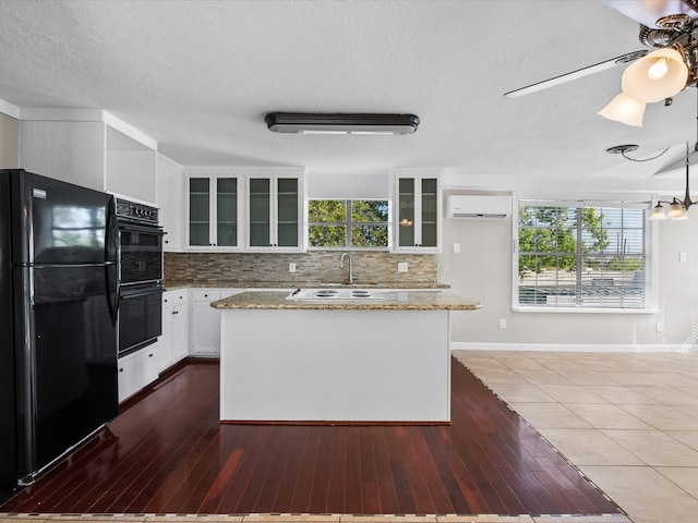 kitchen with backsplash, dark wood-type flooring, white cabinetry, black appliances, and light stone countertops