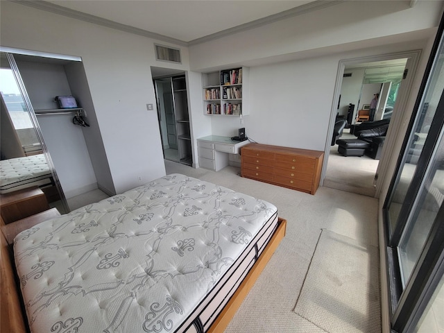 bedroom with a closet, ornamental molding, light colored carpet, and built in desk