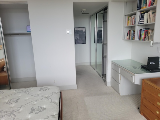 carpeted bedroom with built in desk and a closet