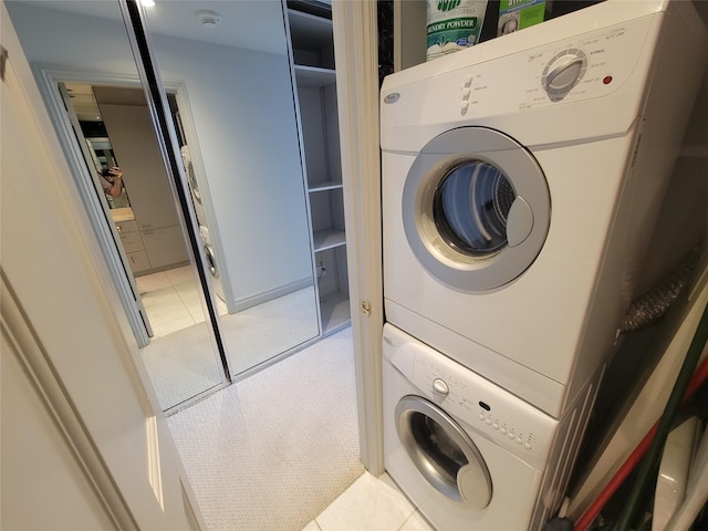 clothes washing area featuring stacked washing maching and dryer and light tile patterned floors