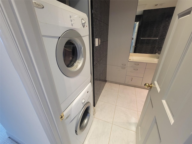 laundry area with stacked washer and clothes dryer and light tile patterned flooring