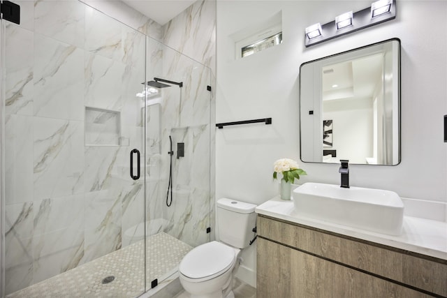 bathroom featuring vanity, a shower with shower door, and toilet