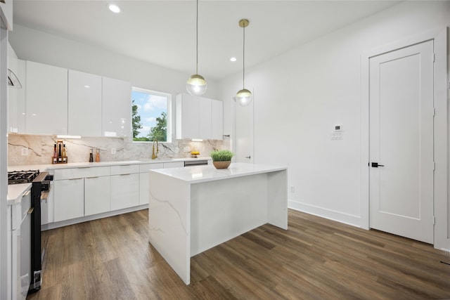 kitchen featuring a kitchen island, hanging light fixtures, stainless steel range with gas cooktop, dark hardwood / wood-style floors, and white cabinets