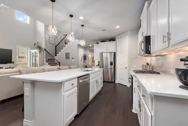 kitchen with tasteful backsplash, light countertops, appliances with stainless steel finishes, dark wood-style floors, and a sink