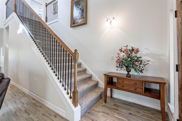 staircase with baseboards and wood finished floors