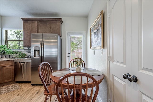 dining room featuring sink, light hardwood / wood-style flooring, and a healthy amount of sunlight