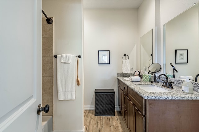 bathroom with tiled shower / bath combo, hardwood / wood-style floors, and vanity