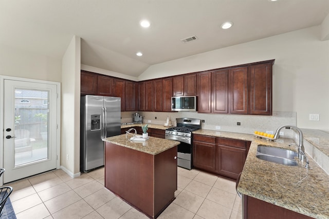 kitchen with lofted ceiling, sink, a center island with sink, stainless steel appliances, and light stone countertops