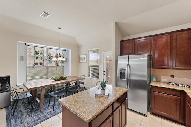 kitchen with pendant lighting, lofted ceiling, stainless steel fridge, light tile patterned floors, and a kitchen island