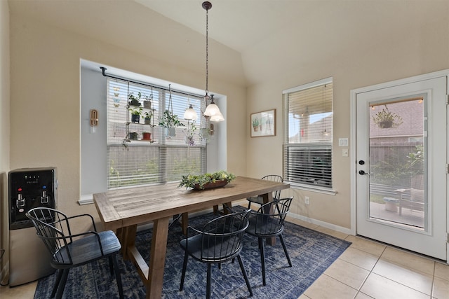 dining area with light tile patterned flooring, a healthy amount of sunlight, and vaulted ceiling