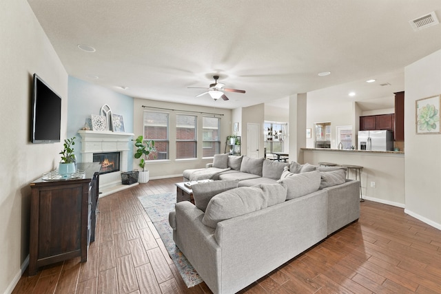 living room featuring ceiling fan, a textured ceiling, and dark hardwood / wood-style floors