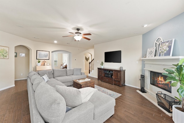 living room with ceiling fan, dark hardwood / wood-style floors, and a tiled fireplace