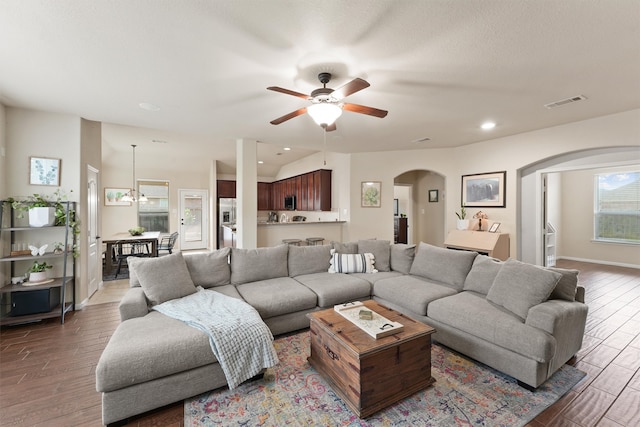 living room featuring dark wood-type flooring and ceiling fan with notable chandelier