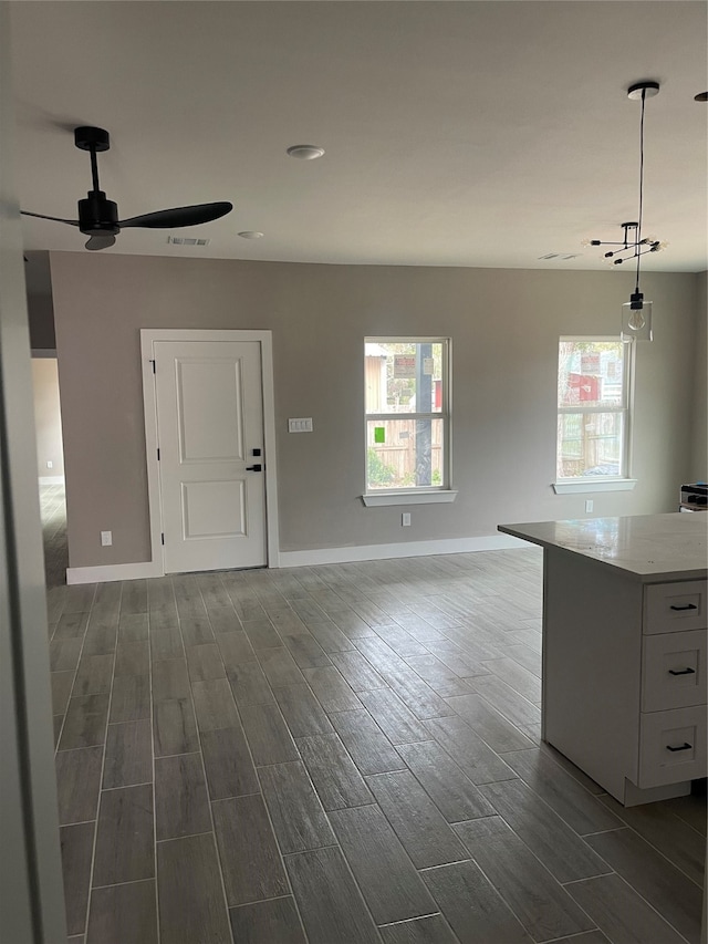 unfurnished living room with ceiling fan, plenty of natural light, and dark wood-type flooring