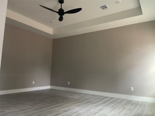 unfurnished room with hardwood / wood-style floors, a tray ceiling, and ceiling fan