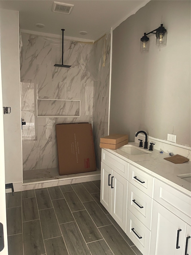 bathroom with vanity, tiled shower, and tile walls