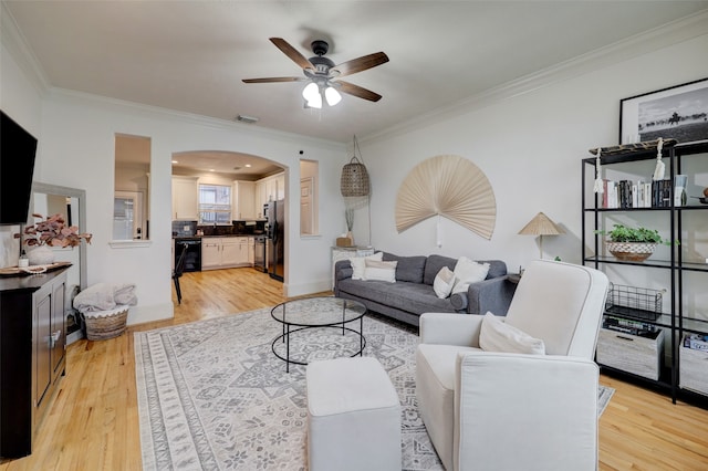 living room with crown molding, light wood-type flooring, and ceiling fan