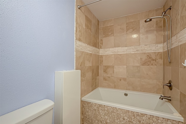 bathroom with tiled shower / bath combo and toilet