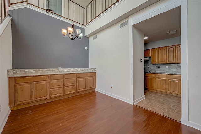 kitchen featuring hardwood / wood-style flooring, a chandelier, hanging light fixtures, and light stone counters